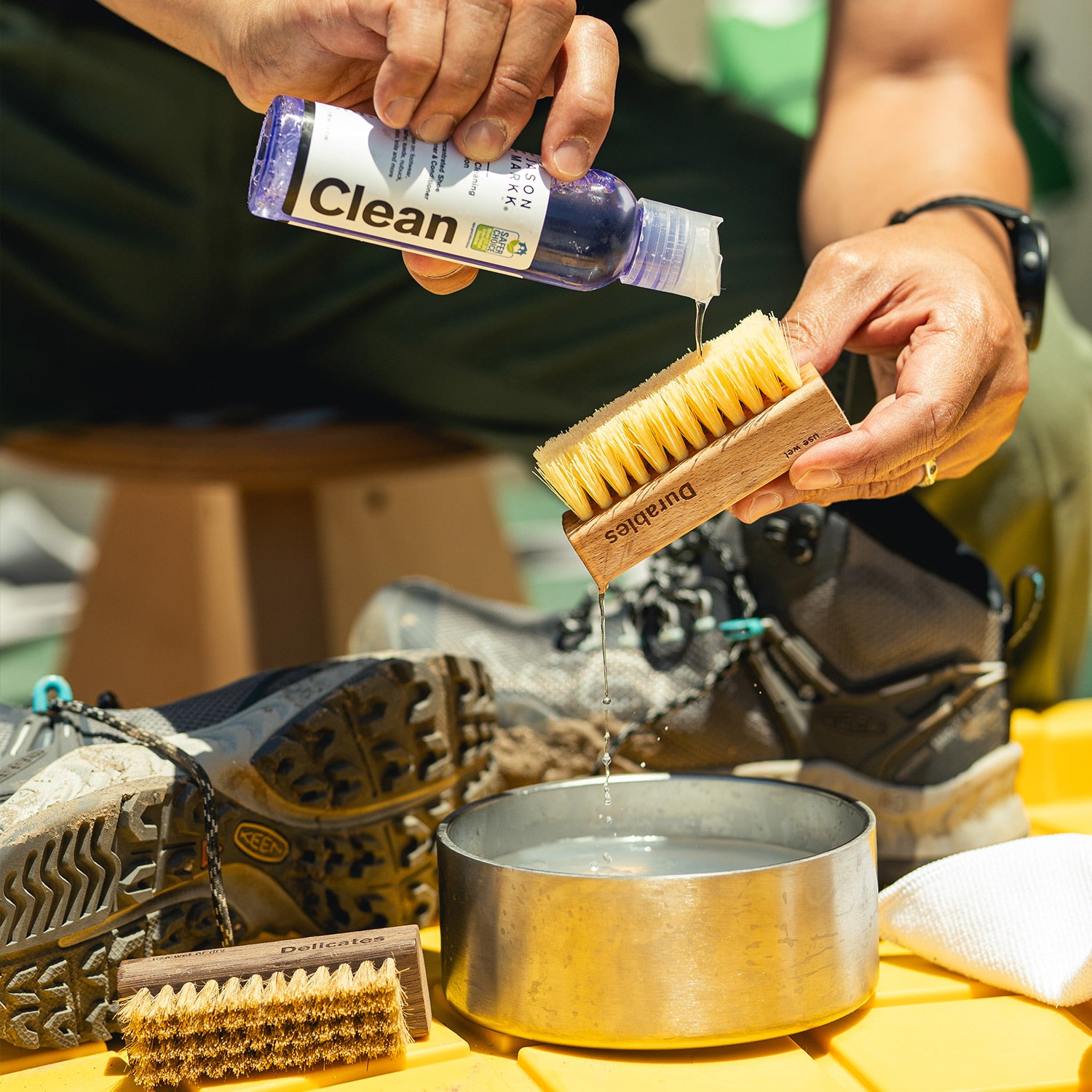 man cleaning his sneakers with jason markk cleaning fluid and brush from essential cleaning kit
