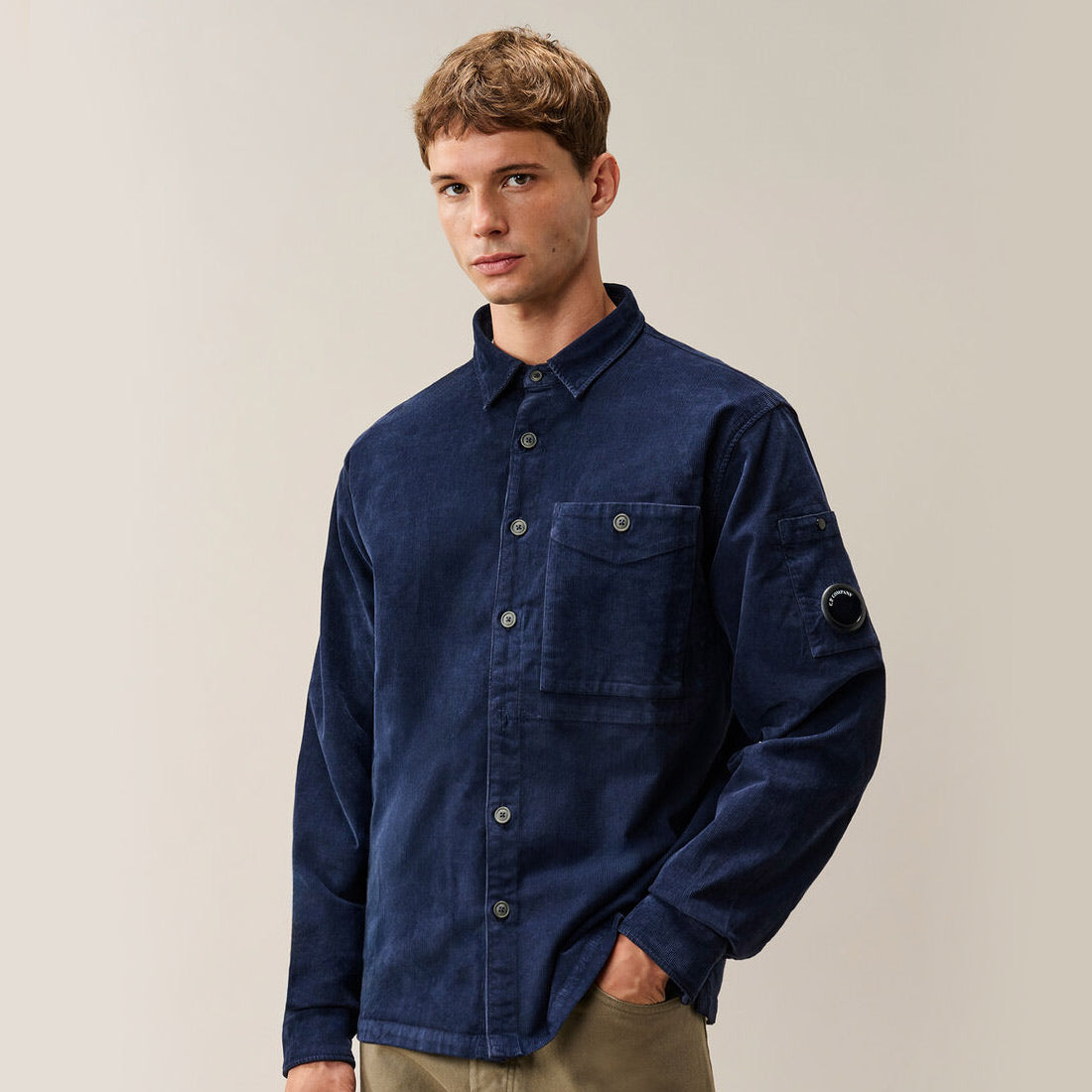 A man wearing a CP Company Corduroy Long Sleeve Lens Button Shirt in Peacoat blue