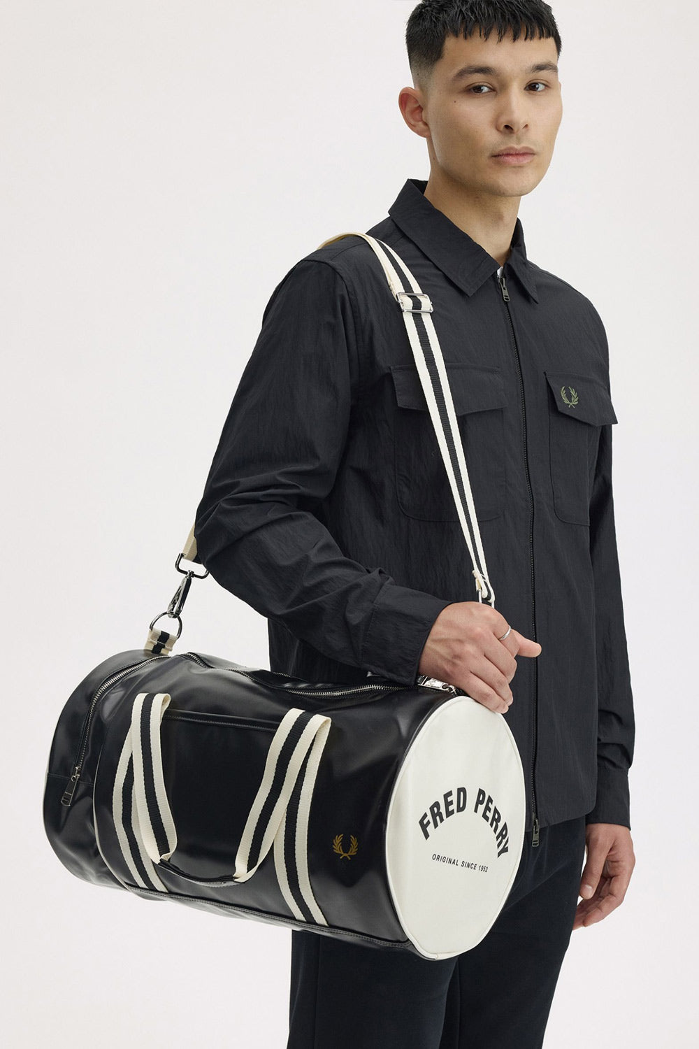 a man wearing the fred perry Classic Barrel Bag Black Ecru over his shoulder