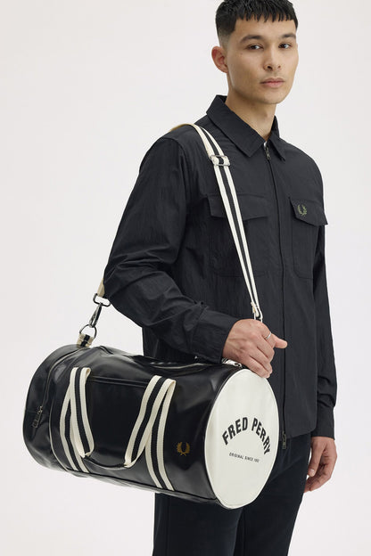 a man wearing the fred perry Classic Barrel Bag Black Ecru over his shoulder