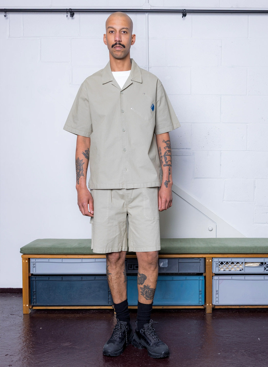 A man standing wearing Pexwear shirt and shorts